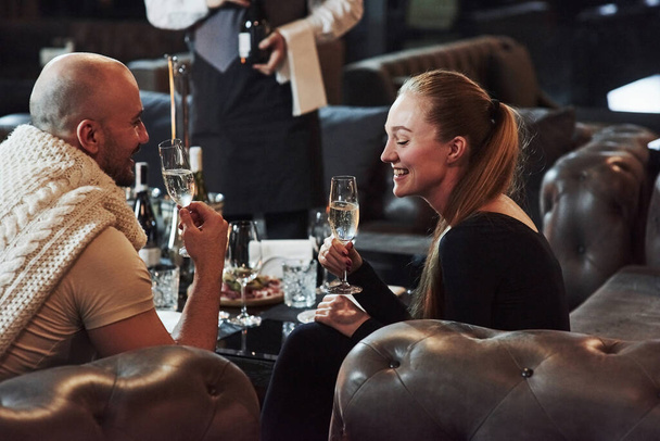 Waiter with the wine. Girl with her boyfriend have nice evening at beautiful restaurant. - Valokuva, kuva