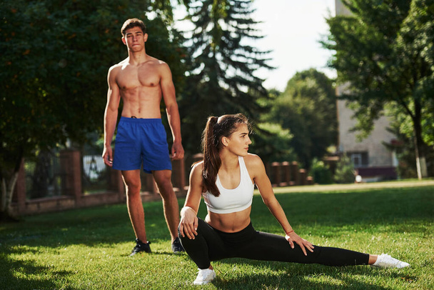 Guys have nice abs. Man and woman have fitness day in the city at daytime in the park. - Foto, Imagem