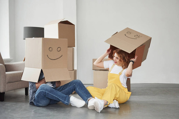 Wearing boxes on the heads. Happy couple together in their new house. Conception of moving. - Foto, Imagen