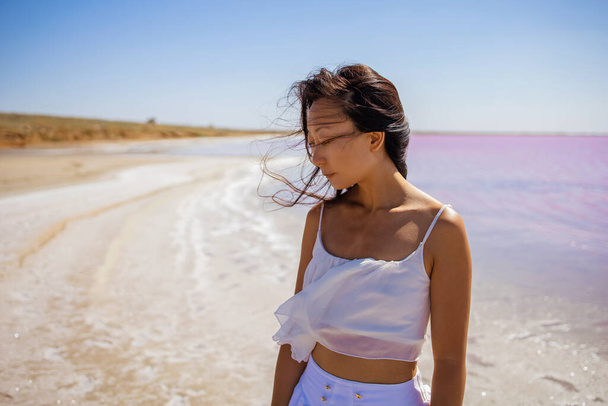 Young asian woman in white meditating near pink lake, practicing Yoga standing on the beach. - Fotoğraf, Görsel