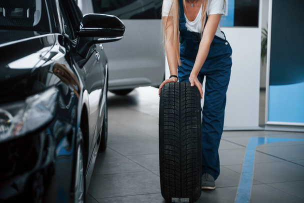 Woman walks with brand new wheel to the car. Conception of repair. - Foto, Imagem