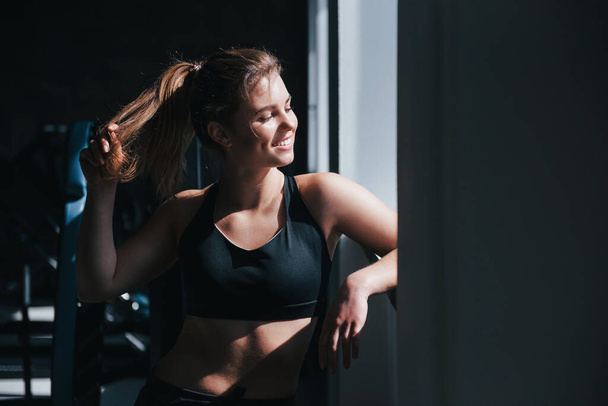 Warm sunlight. Photo of gorgeous blonde woman in the gym at her weekend time. - Foto, afbeelding