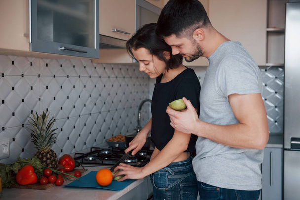 Helping each other. Young couple in the modern kitchen at home at their weekend time in the morning. - Foto, Imagen