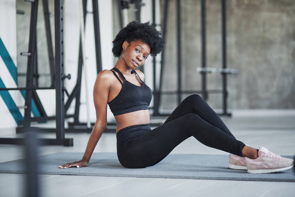 Black wear. African american woman with curly hair and in sportive clothes have fitness day in the gym. - Fotoğraf, Görsel