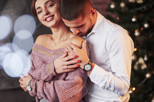 Frau lächelt in die Kamera. Nettes Paar feiert Neujahr drinnen mit klassisch schönen Kleidern. - Foto, Bild