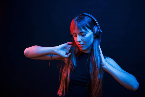 Dance to the rhythm. Studio shot in dark studio with neon light. Portrait of young girl. - Fotó, kép