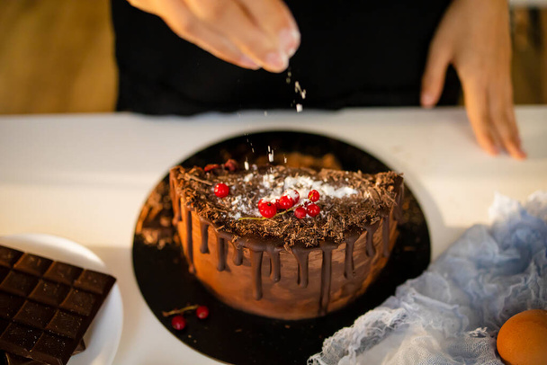 クロップドシェフがテーブルで菓子職人やパン職人の料理を閉じます。チョコレートクリームアプリケーションケーキ作りプロセス.  - 写真・画像