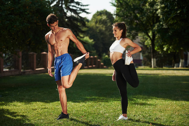 Exercises for legs. Man and woman have fitness day in the city at daytime in the park. - Foto, Imagem