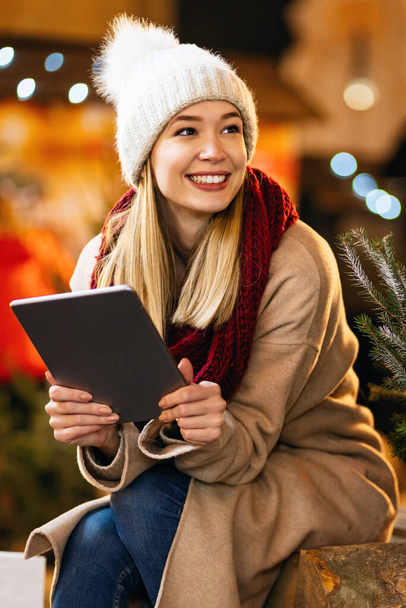 Shopping christmas travel people concept. Beautiful woman with shopping bags using digital device outdoors - Foto, Imagen