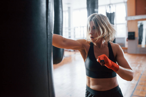 Productieve weekenden. Vrouwelijke bokser slaat op de zak. Blond hebben oefening in de sportschool. - Foto, afbeelding