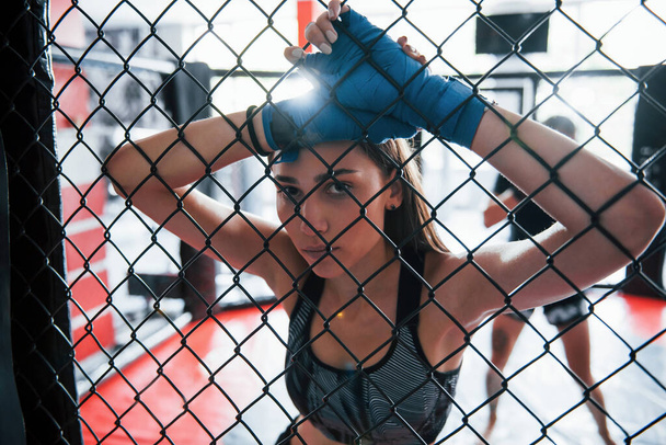 Taking a break. Sportswoman at boxing ring have exercise. Leaning on the fence. - Foto, afbeelding