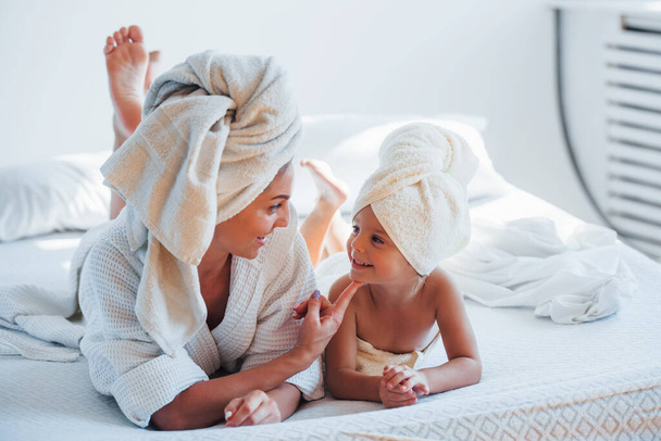 Young mother with her daugher have beauty day indoors in white room. - Foto, immagini