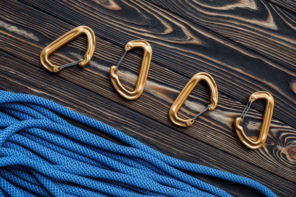 View from the top. Isolated photo of climbing equipment. Part of carabiner lying on the wooden table. - Foto, immagini
