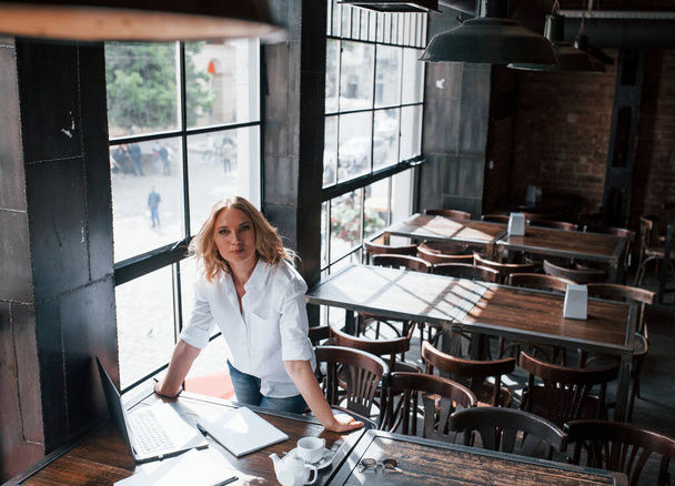 Good mood. Businesswoman with curly blonde hair indoors in cafe at daytime. - 写真・画像