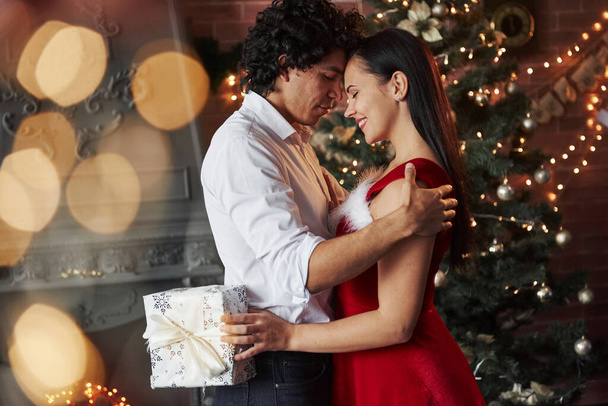 Girl holds white gift box. New Year's evening dancing. Lovely gorgeous couple spending time together. - Foto, Imagem