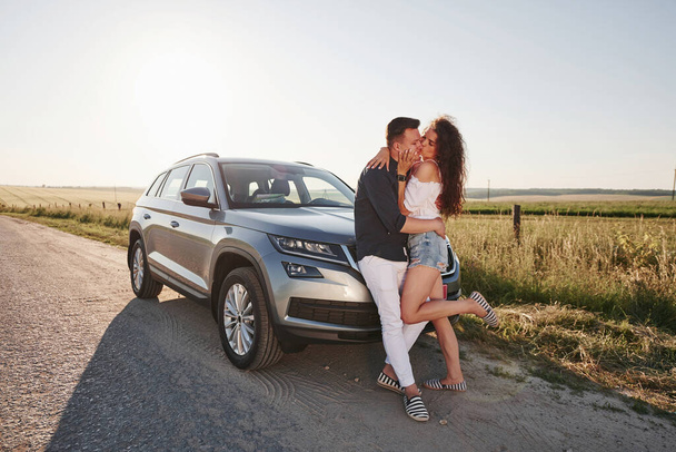 Lovely couple near their new modern car at weekend time. - Foto, imagen