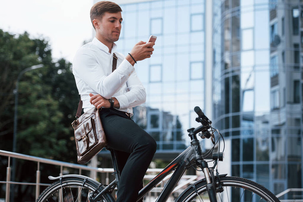 Reading news. Businessman in formal clothes with black bicycle is in the city. - Zdjęcie, obraz