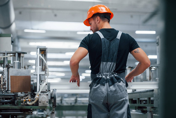 Taking the window. Industrial worker indoors in factory. Young technician with orange hard hat. - Fotó, kép