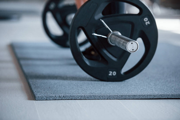Grounded view. Cropped photo of woman doing squatting with barbell in the gym. - 写真・画像