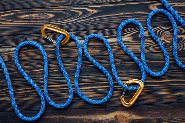 Long blue knot. Isolated photo of climbing equipment. Parts of carabiners lying on the wooden table. - Foto, immagini