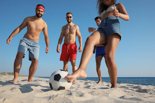 Group of friends playing football on beach - Foto, afbeelding