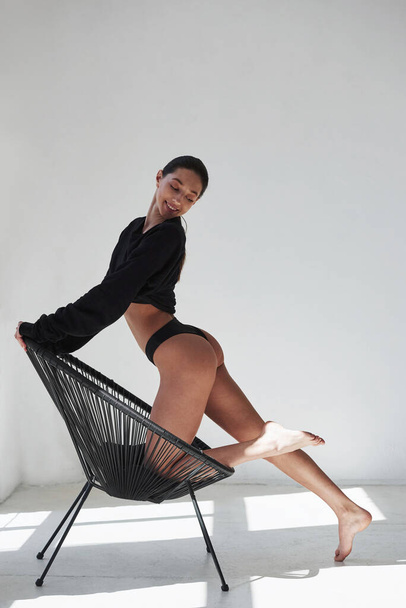 Modern designed chair. Caucasian pretty woman stands against white background in the studio. - Photo, Image
