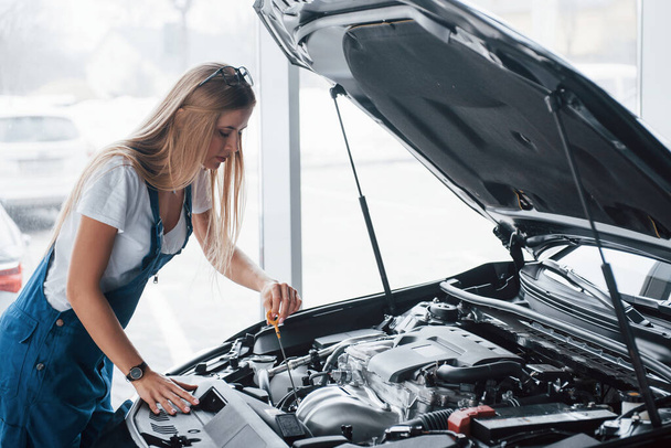 No breaks, all must be perfectly done. On the lovely job. Car addicted woman repairs black automobile indoors. - Foto, Imagem