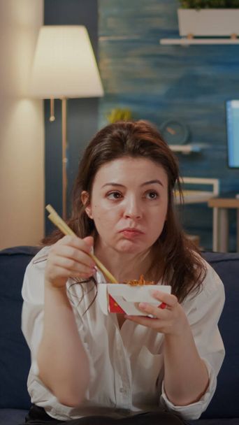Γυναίκα τρώει κινέζικο φαγητό από takeaway τόπο κάθεται στον καναπέ - Φωτογραφία, εικόνα