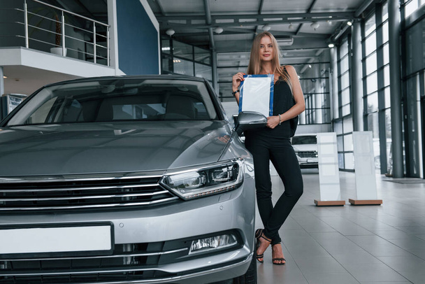 Perfectly polished automobile. Girl and modern car in the salon. At daytime indoors. Buying new vehicle. - Valokuva, kuva