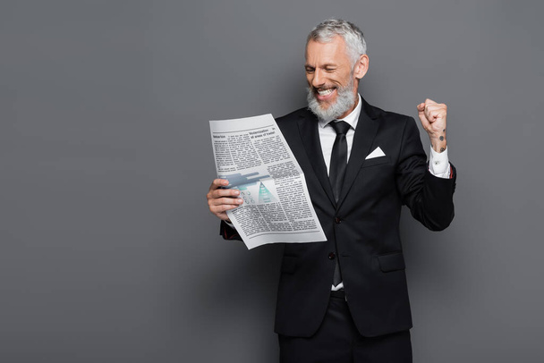 happy middle aged businessman reading newspaper on grey - Foto, imagen