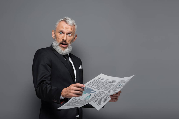 surprised middle aged businessman holding newspaper on grey - Фото, зображення