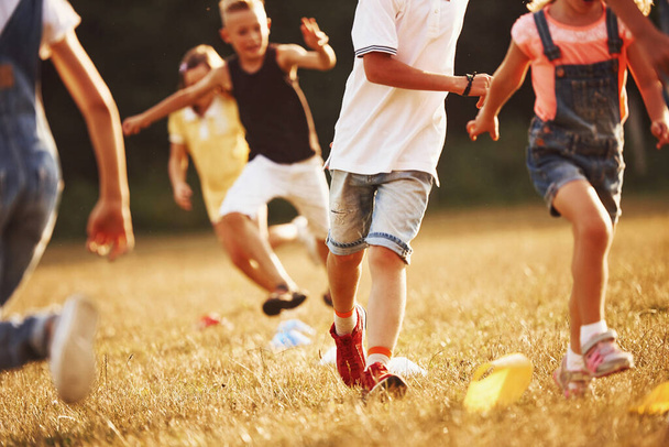 Through obstacles. Kids running in the field at sunny day. Conception of healthy lifestyle. - Фото, изображение