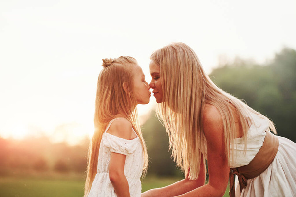 Blurred background. Mother and daughter enjoying weekend together by walking outdoors in the field. Beautiful nature. - Photo, image