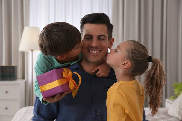 Man receiving gift for Father's Day from his children at home - Фото, изображение
