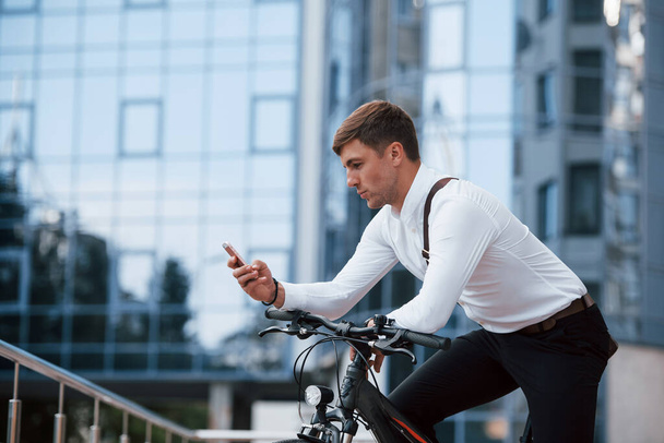 Answers the message. Businessman in formal clothes with black bicycle is in the city. - 写真・画像