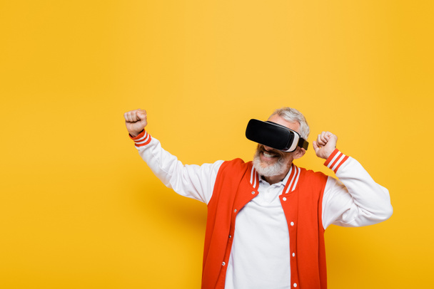 smiling middle aged man in bomber jacket and vr headset gesturing on yellow - Foto, imagen
