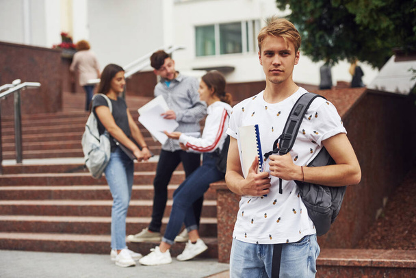 Guy posing for the camera. Group of young students in casual clothes near university at daytime. - Fotoğraf, Görsel