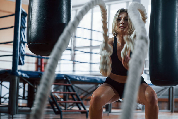 Boxing ring behind. Blonde sport woman have exercise with ropes in the gym. Strong female. - Foto, Imagem