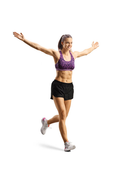 Full length shot of a fit young woman running and spreading arms wide open isolated on white background - Foto, Imagem