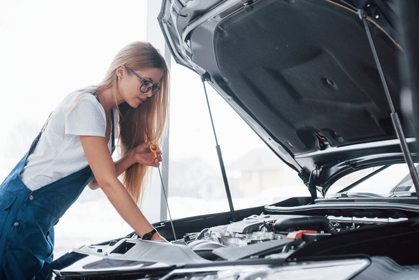 High levels service. On the lovely job. Car addicted woman repairs black automobile indoors. - Φωτογραφία, εικόνα