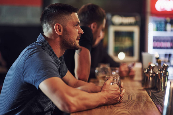 Side view. Friends resting in the pub with beer in hands. Having conversation. - Fotó, kép