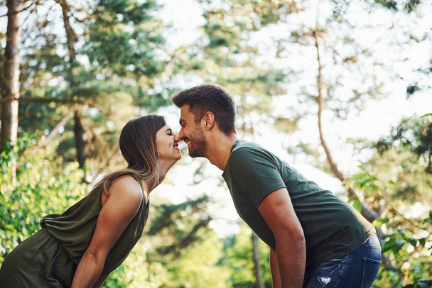 Side view. Beautiful young couple have a good time in the forest at daytime. - Fotoğraf, Görsel