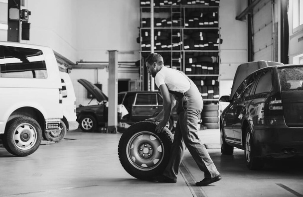 Black and white colored. Employee in uniform works in the automobile salon. - Фото, зображення