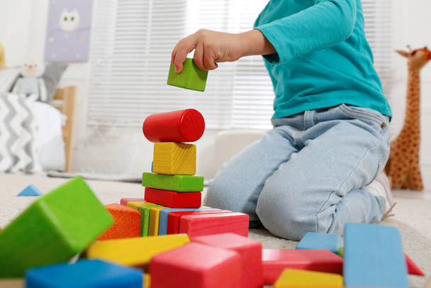 Cute little girl playing with colorful building blocks at home, closeup - Fotó, kép