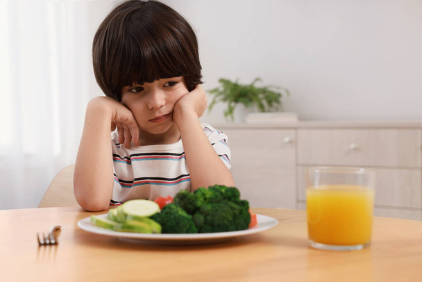 Lindo niño negándose a comer verduras en casa - Foto, Imagen