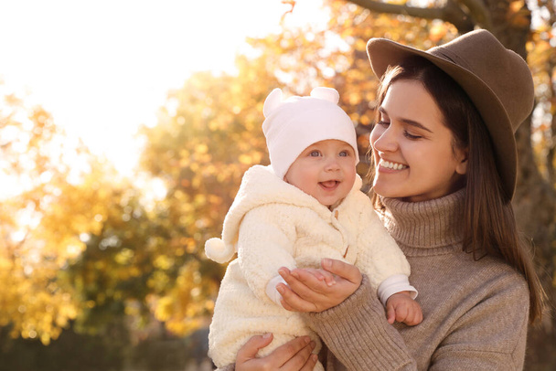 Happy mother with her baby daughter in park on sunny autumn day, space for text - Photo, Image
