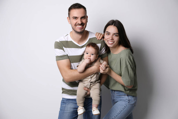 Happy family. Couple with their cute baby on grey background - Foto, Imagem