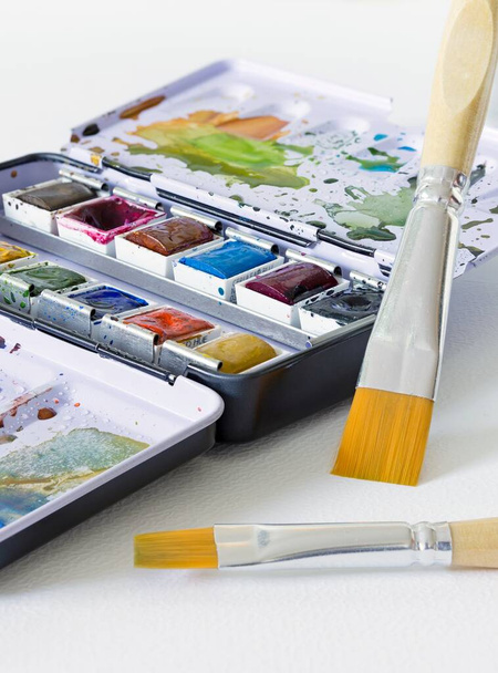 An artist's metal compact travel paint tin with watercolour paints and brushes. - Photo, Image