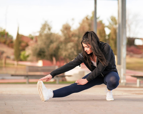 mujer joven y atractiva consultando el mvil en un parque mientras hace yoga y deporte al aire libre - Fotó, kép