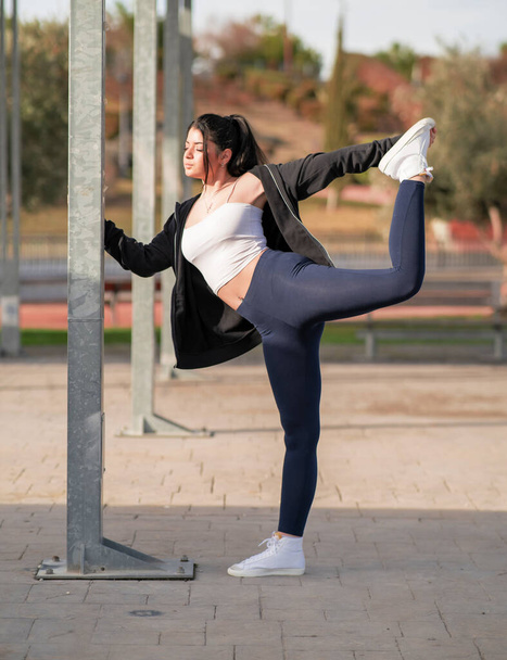 mujer joven y atractiva consultando el mvil en un parque mientras hace yoga y deporte al aire libre - Photo, Image
